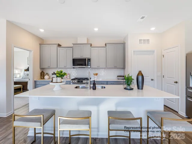 a kitchen with stainless steel appliances granite countertop a stove top oven a sink dishwasher and white cabinets with wooden floor