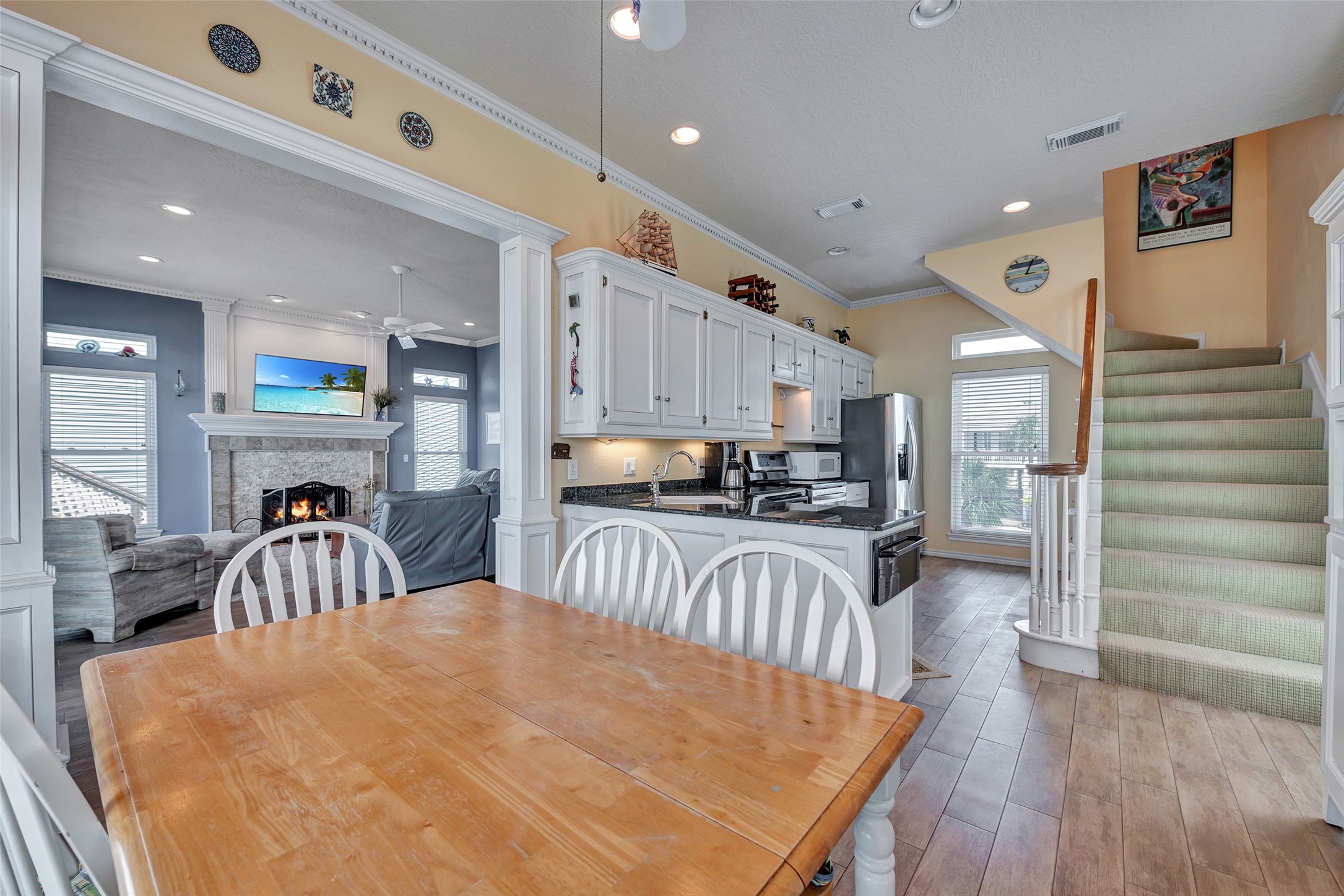 247 Isles End Road Tiki Island, TX 77554 - Photo 11 of 48 Kitchen & Dining Combo is thoughtfully designed space brings together the kitchen and dining area with ease, featuring white cabinetry, granite countertops, and wood-look tile flooring. Ideal for casual meals, entertaining, or enjoying the natural light pouring in from every angle.