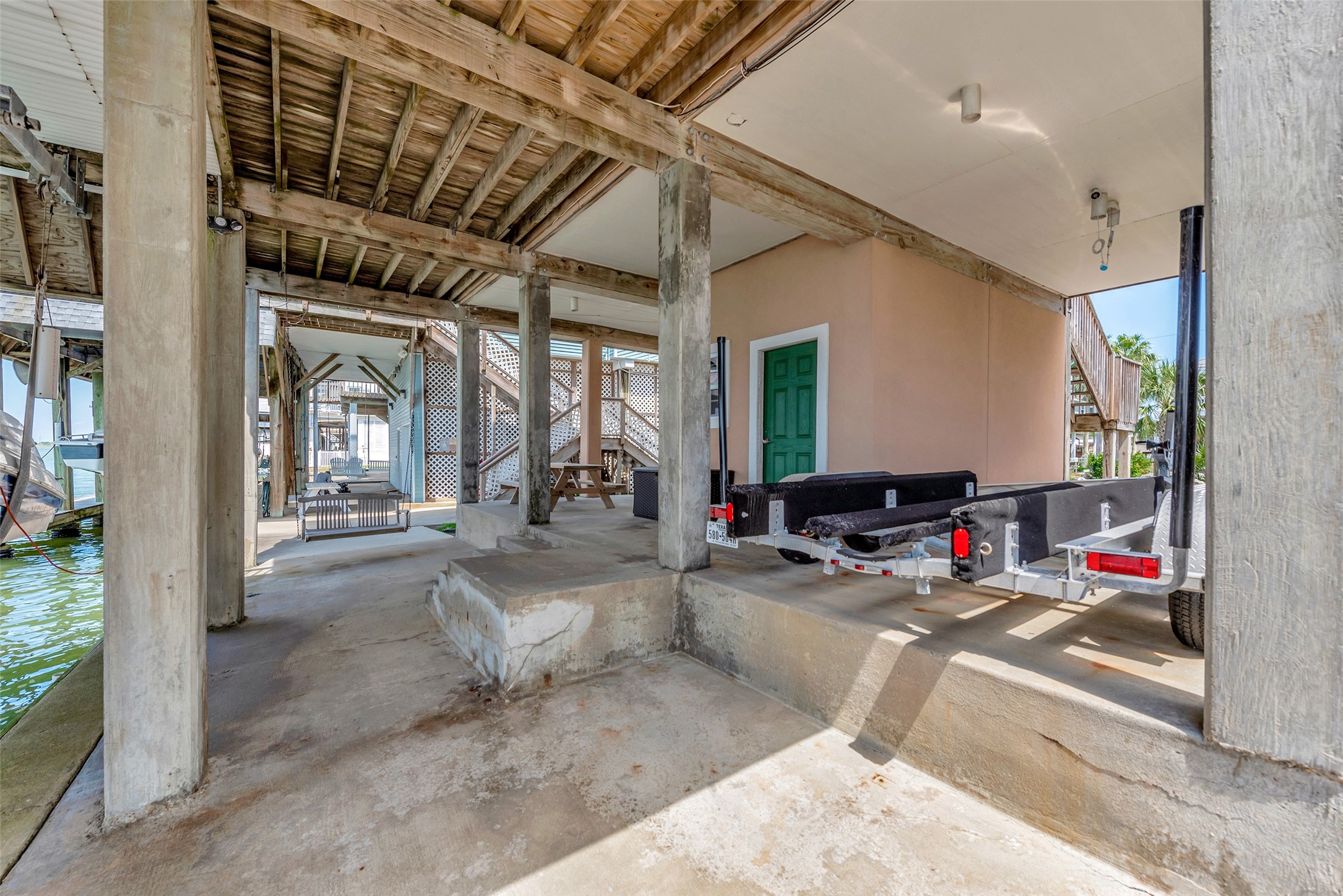 247 Isles End Road Tiki Island, TX 77554 - Photo 32 of 48 Underneath the home, you'll find a spacious covered deck and carport area that’s perfect for staying cool in the shade. There’s room for a trailer, seating, and easy access to the dock.