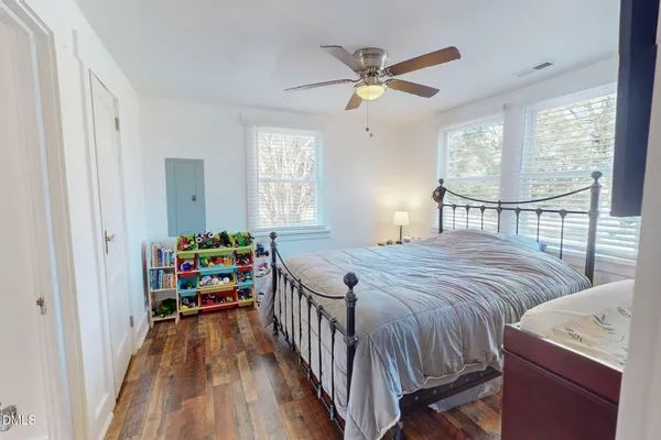 a bedroom with a bed a chandelier and windows