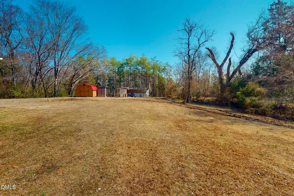 a view of dirt field with trees in the background