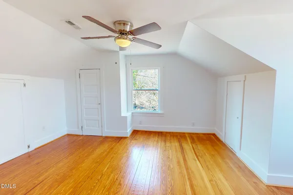 a view of empty room with wooden floor and fan