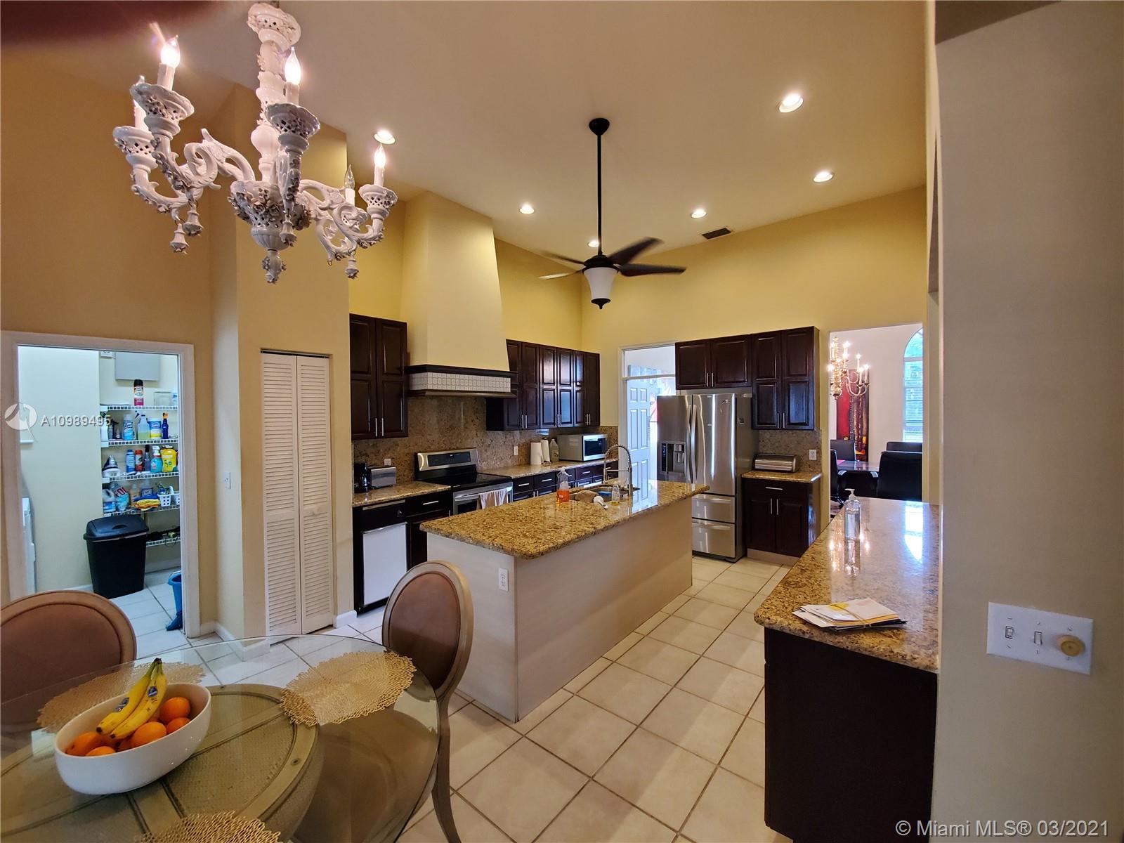 1405 Addison Avenue Boca Raton, FL 33486 - Photo 4 of 24 a kitchen with granite countertop kitchen island stainless steel appliances a stove refrigerator a sink dishwasher a dining table and chairs with wooden floor