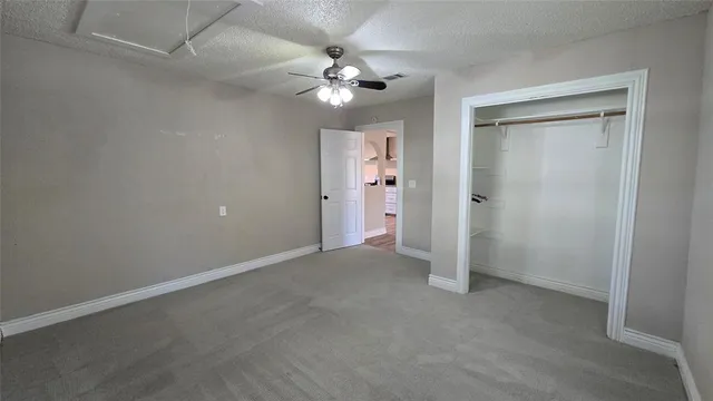 an empty room with closet and a chandelier fan