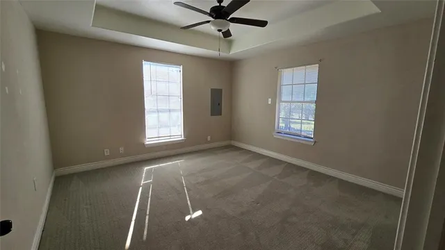 an empty room with windows and fan