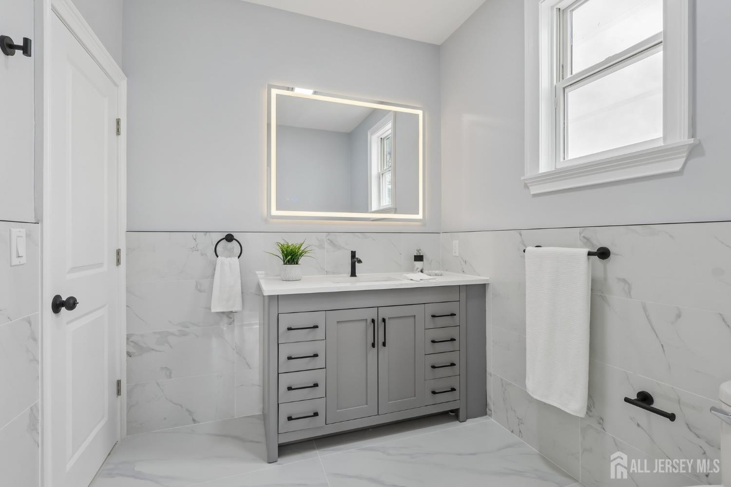 239 Suttons Lane Edison, NJ 08817 - Photo 46 of 68 a bathroom with a granite countertop sink a mirror a vanity and a shower