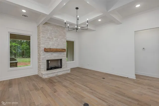 an empty room with windows a fireplace a ceiling fan and wooden floor