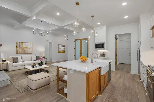 a large white kitchen with a large island oven a stove a dining table and chairs