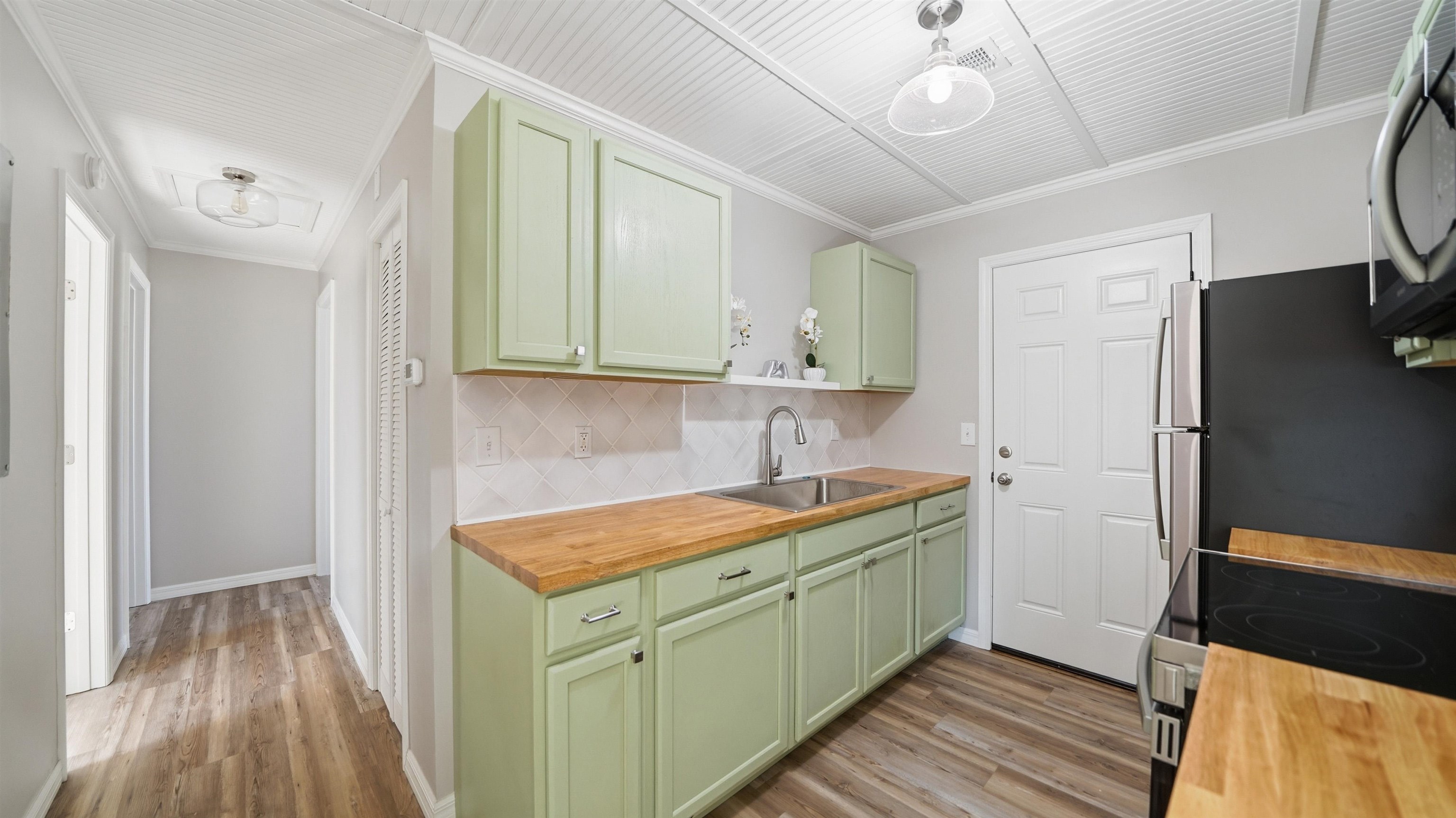 811 Hymon Circle Bunnell, FL 32110 - Photo 1 of 32 Kitchen with wood counters, green cabinetry, crown molding, appliances with stainless steel finishes, and light wood finished floors