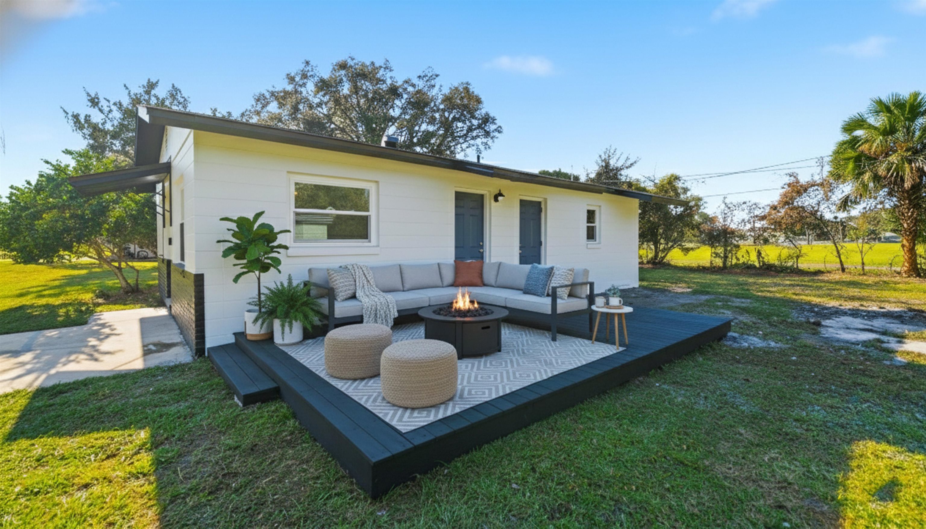 811 Hymon Circle Bunnell, FL 32110 - Photo 11 of 32 Back of property featuring a lawn, a patio area, a deck, and an outdoor living space with a fire pit
