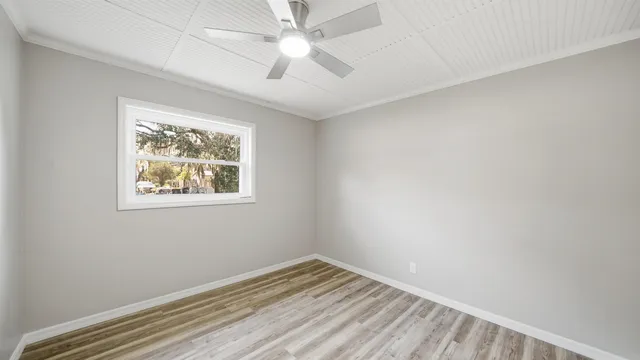 an empty room with a window and ceiling fan