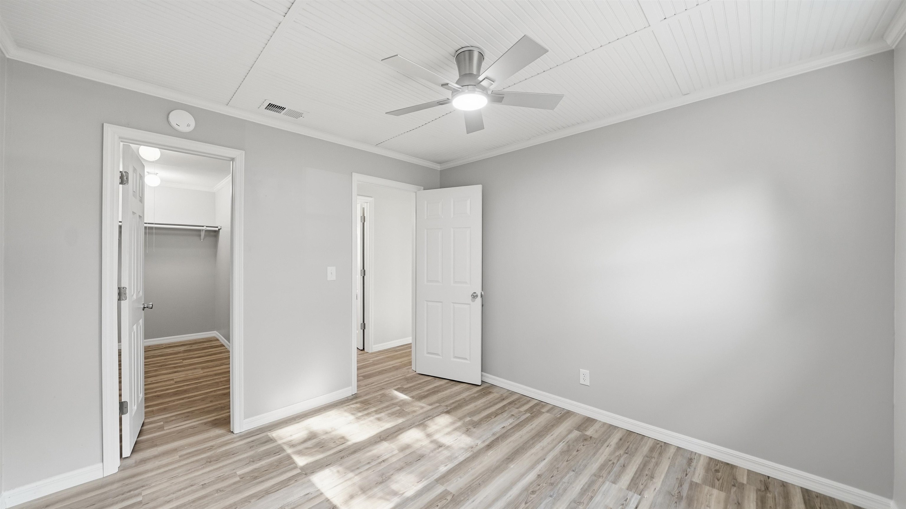 811 Hymon Circle Bunnell, FL 32110 - Photo 4 of 32 Unfurnished bedroom with a spacious closet, ceiling fan, ornamental molding, and light wood-type flooring