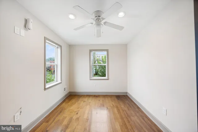 an empty room with wooden floor and ceiling fan
