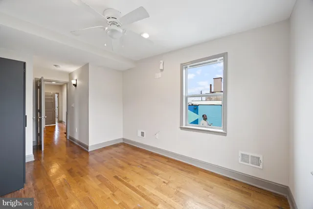 a view of an empty room with a window and wooden floor
