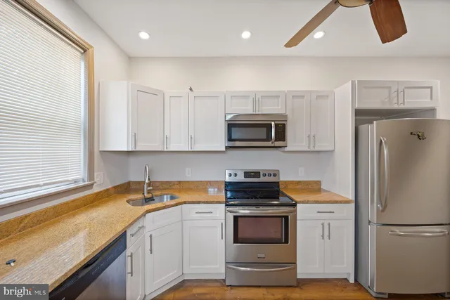 a kitchen with stainless steel appliances granite countertop a refrigerator a stove and a sink