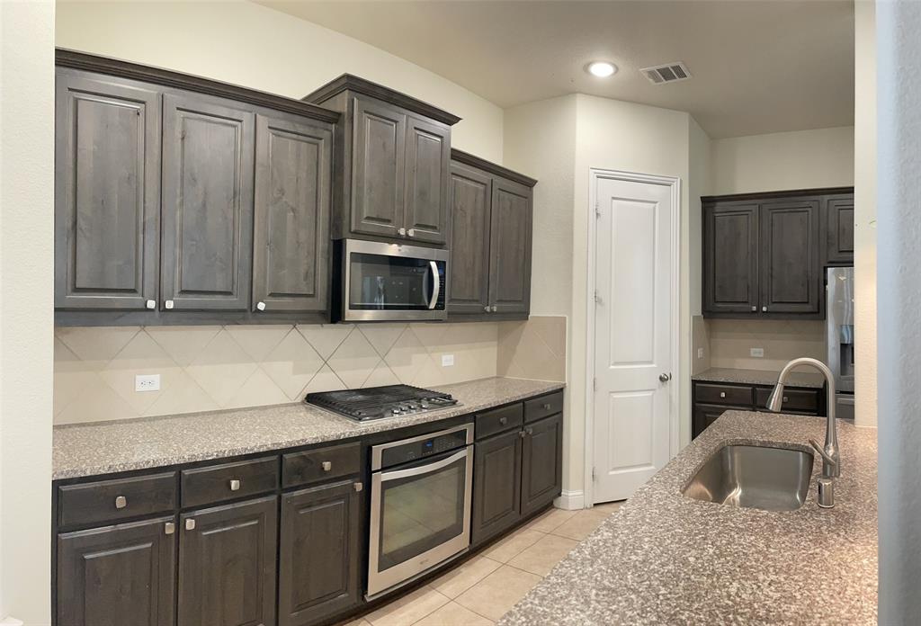 8031 Sunflower Lane Dallas, TX 75252 - Photo 15 of 34 a kitchen with granite countertop a sink dishwasher stove and cabinets