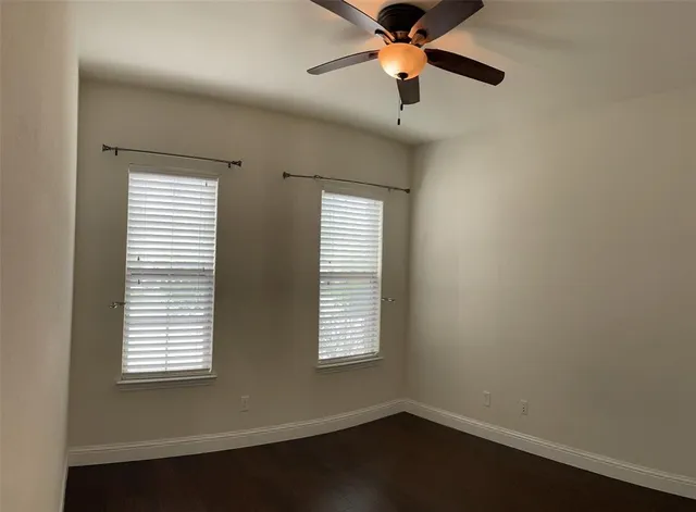 an empty room with wooden floor fan and windows
