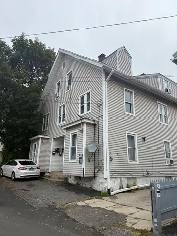 a white house that has a tree on the side of it