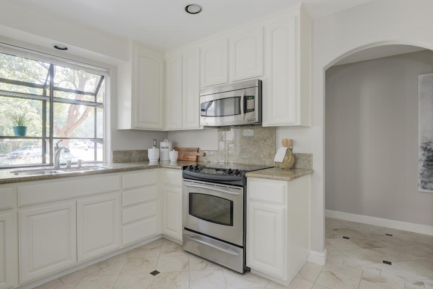 928 Wright Avenue, Unit 401 Mountain View, CA 94043 - Photo 5 of 18 a kitchen with granite countertop white cabinets and a stove top oven