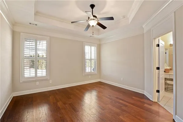 an empty room with wooden floor chandelier fan and windows