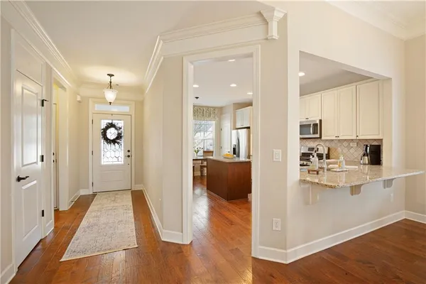 a kitchen with granite countertop a sink stove refrigerator and white cabinets with wooden floor