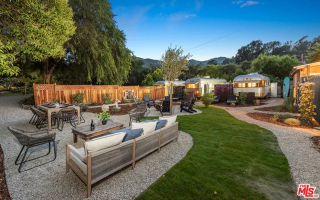 a view of a patio with couches and a fire pit and large trees