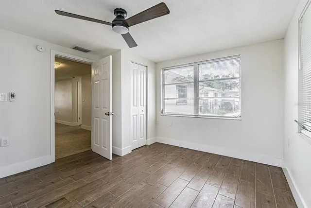 a view of empty room with wooden floor and fan