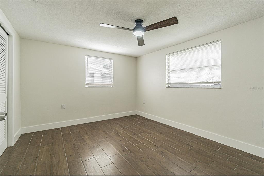5631 Riddle Road Holiday, FL 34690 - Photo 16 of 27 an empty room with wooden floor ceiling fan and windows