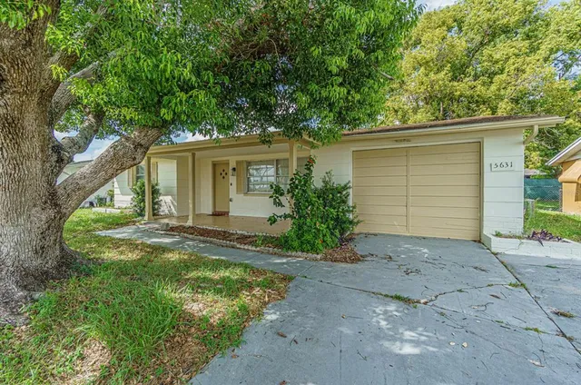 front view of house with a yard and trees all around