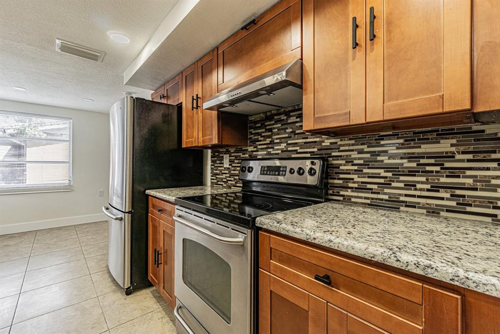 5631 Riddle Road Holiday, FL 34690 - Photo 7 of 27 a kitchen with granite countertop a stove and a microwave