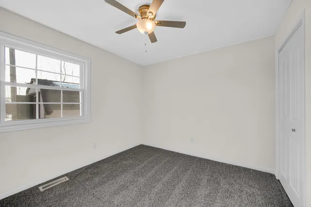 an empty room with a window and a fan