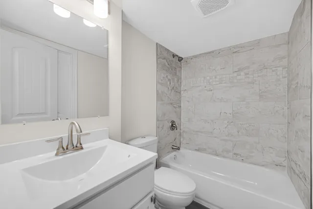 a bathroom with a bathtub shower sink vanity and toilet