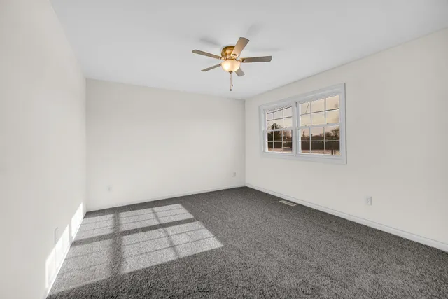an empty room with windows and ceiling fan