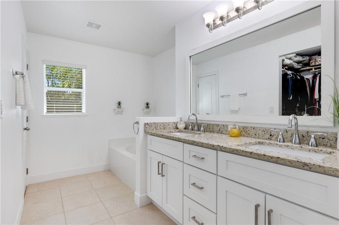 402 Lexington Avenue Southwest Vero Beach, FL 32962 - Photo 18 of 33 a bathroom with a granite countertop sink a large mirror and a window