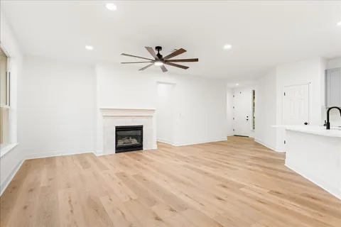 a view of a livingroom with a fireplace a ceiling fan and wooden floor