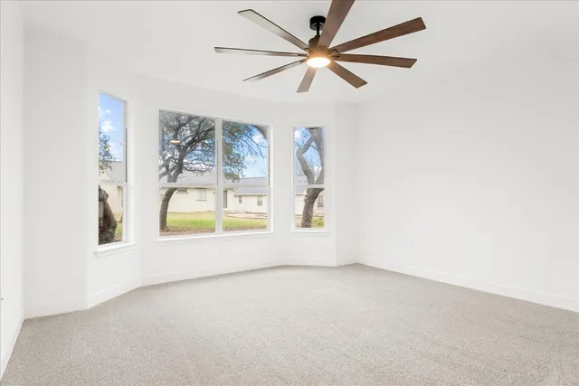 an empty room with a window and a ceiling fan