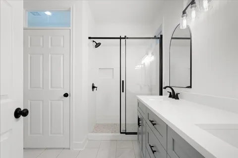 a bathroom with a double vanity sink mirror and shower