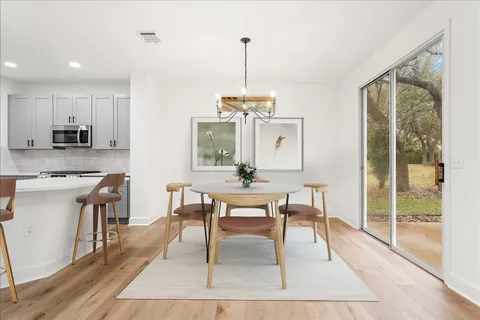 a dining room with wooden floor a glass table and chairs