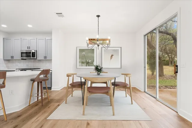 a dining room with wooden floor a glass table and chairs
