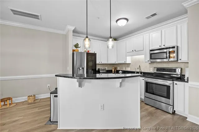 a kitchen with stainless steel appliances a stove a sink and white cabinets