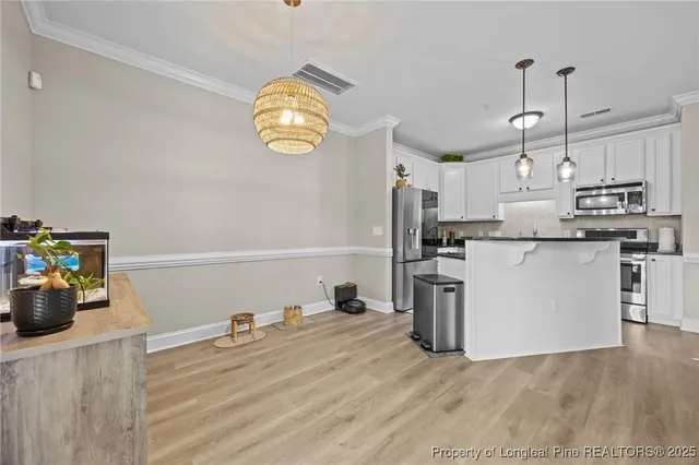 a view of a kitchen with stainless steel appliances granite countertop a sink a stove and wooden floors