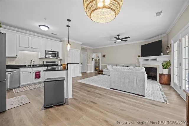 a large kitchen with stainless steel appliances kitchen island granite countertop a stove top oven a sink dishwasher a dining table and chairs with wooden floor