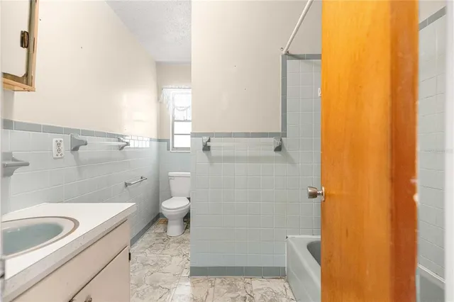 a bathroom with a granite countertop toilet a sink and a bathtub