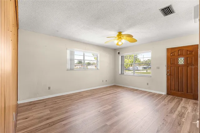 a view of an empty room with window and wooden floor