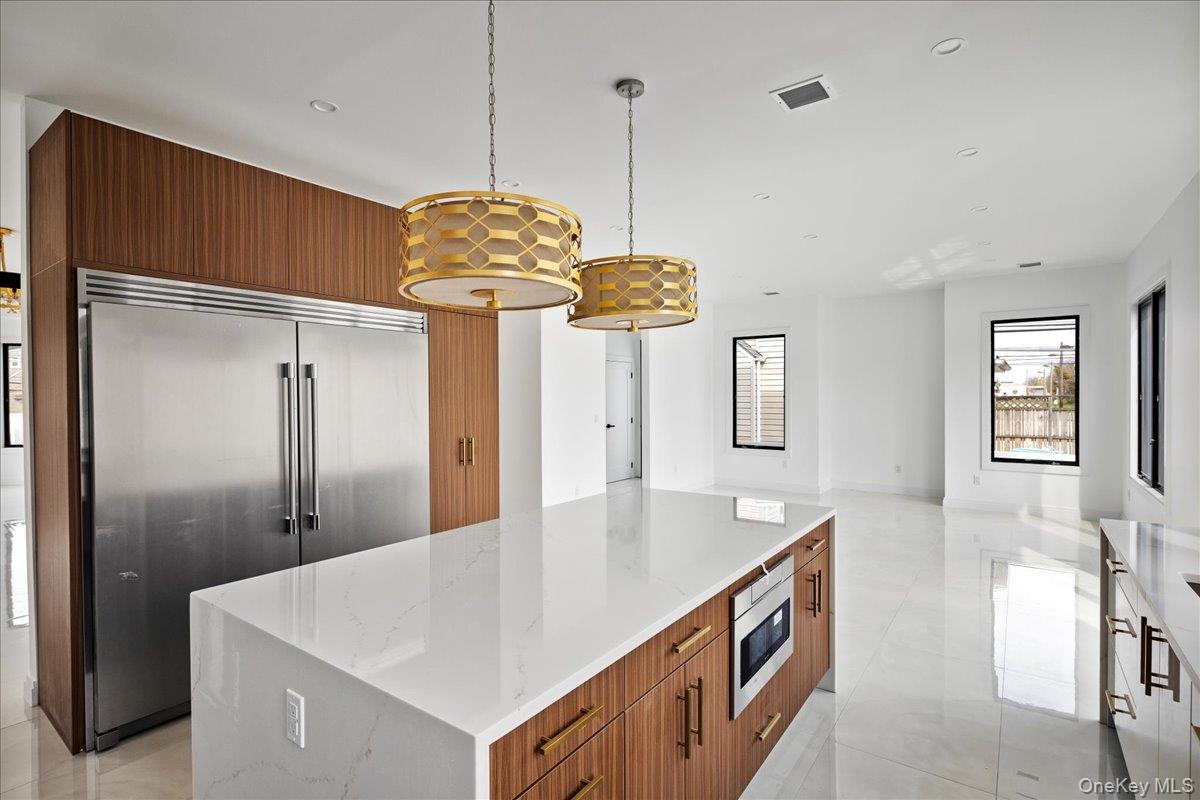544 Arlington Road Cedarhurst, NY 11516 - Photo 17 of 38 a large kitchen with stainless steel appliances granite countertop a sink a refrigerator and a chandelier