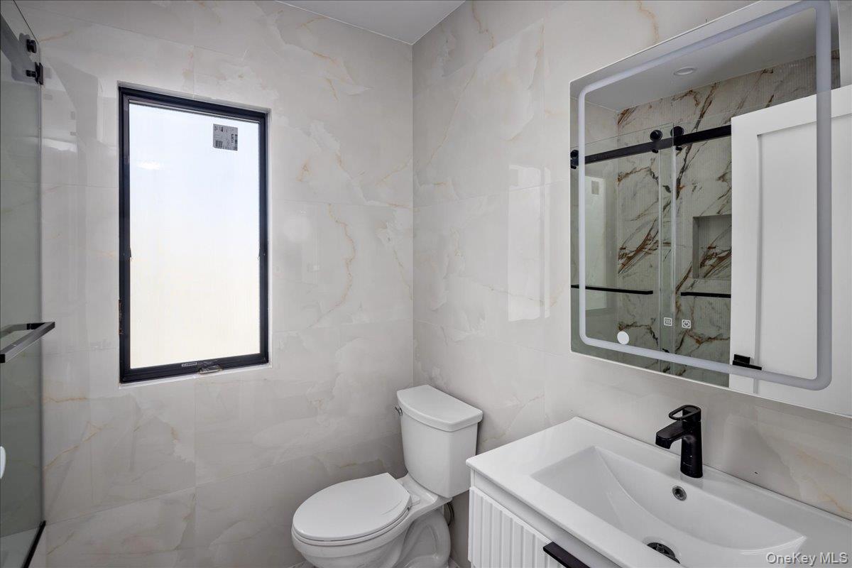 544 Arlington Road Cedarhurst, NY 11516 - Photo 29 of 38 a bathroom with a sink a mirror and a toilet