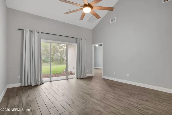 a view of an empty room with a window and wooden floor