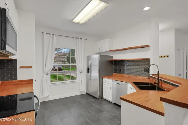 an empty room with wooden floor chandelier and windows