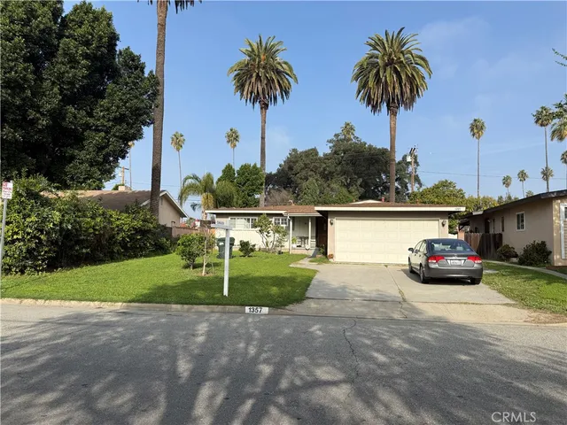 a view of a house with a yard and palm trees