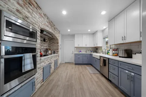 a kitchen with stainless steel appliances kitchen island granite countertop a stove a sink and white cabinets